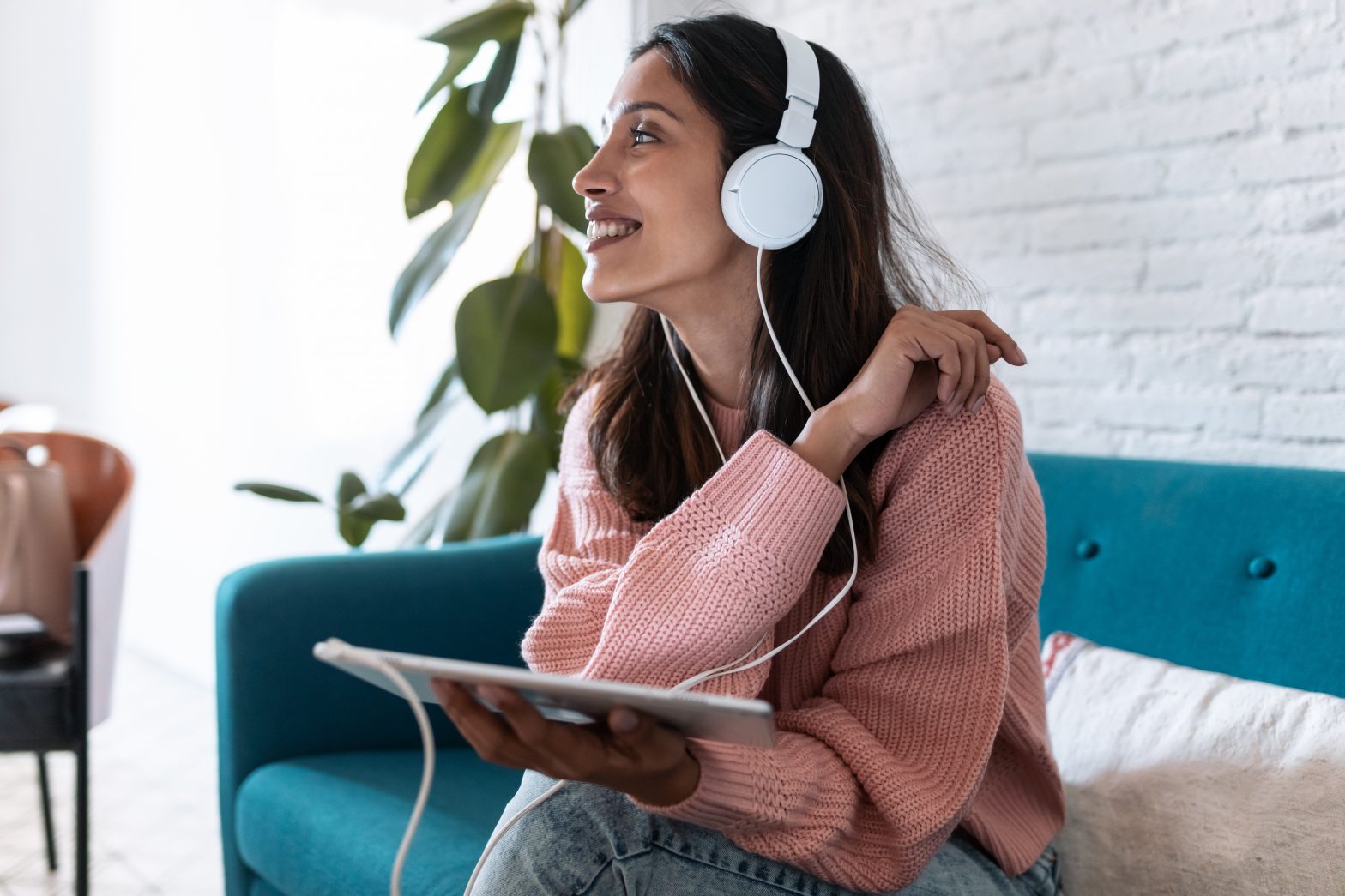 Young woman listening to music with digital tablet while sitting on sofa