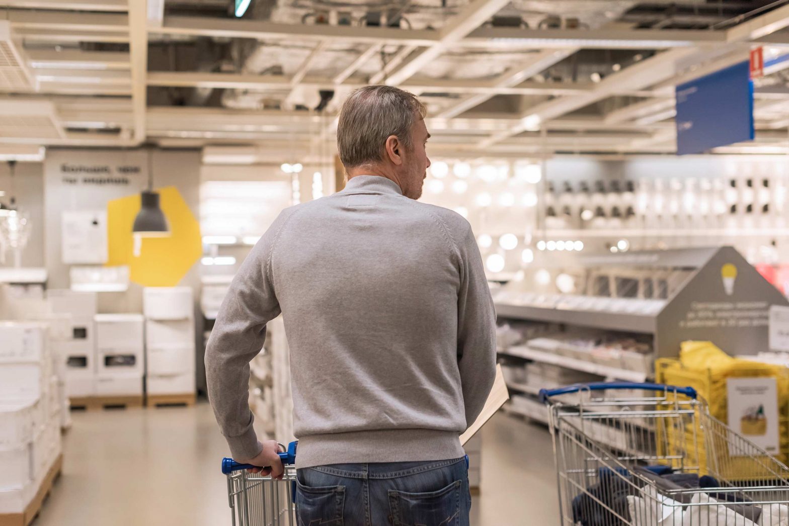 Back view of shopper walking with trolley in a large hardware store