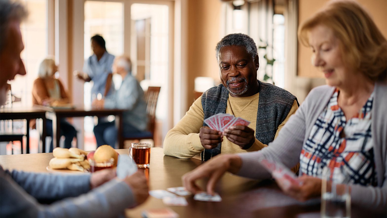 Happy black senior plays cards with friends in an independent living facility