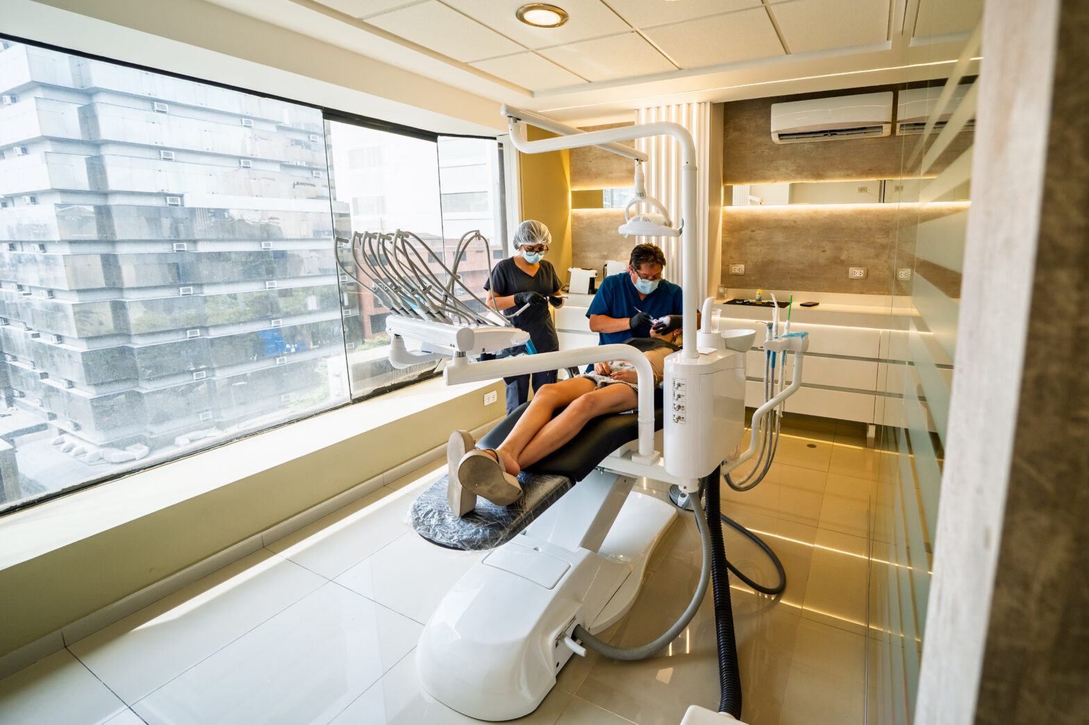 A man reclining in a dental chair while the dentist and hygienist look at his teeth